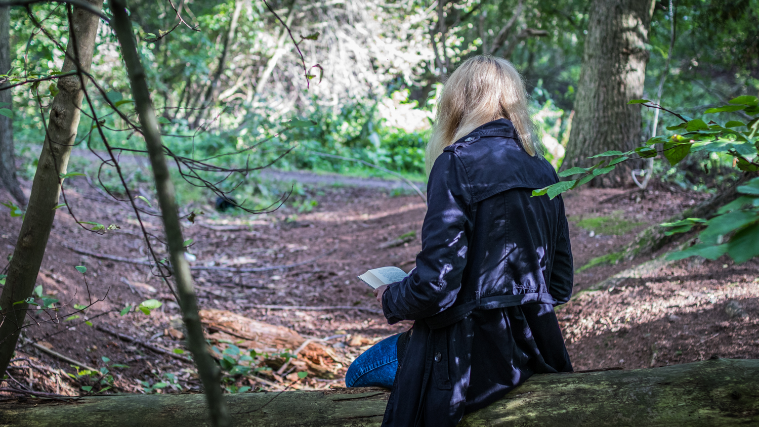 A young woman (me) reading a book in the forest