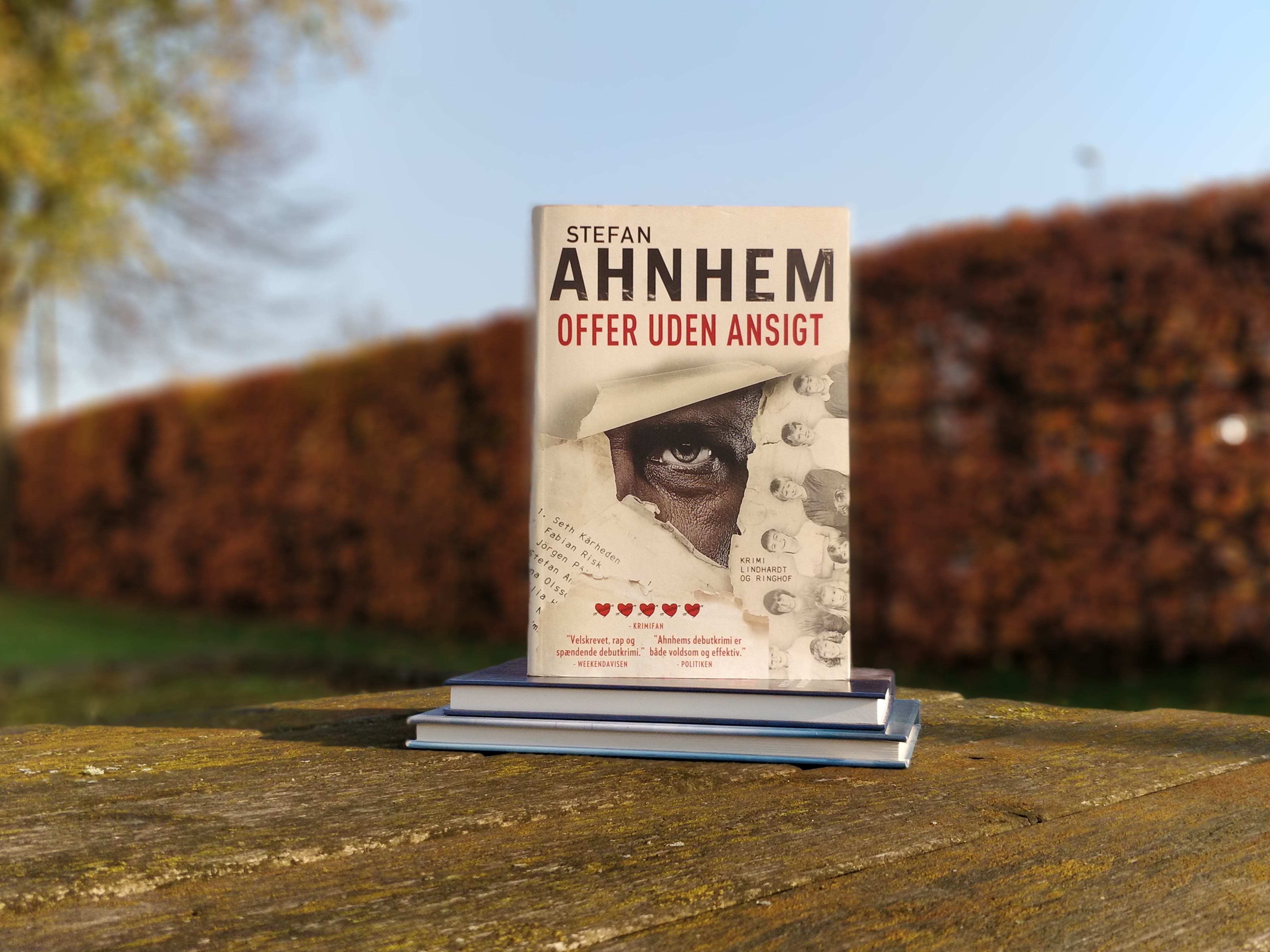 På et udendørsbord ligger to bøger, og oven på disse står bogen Offer uden ansigt af Stefan Ahnhem.