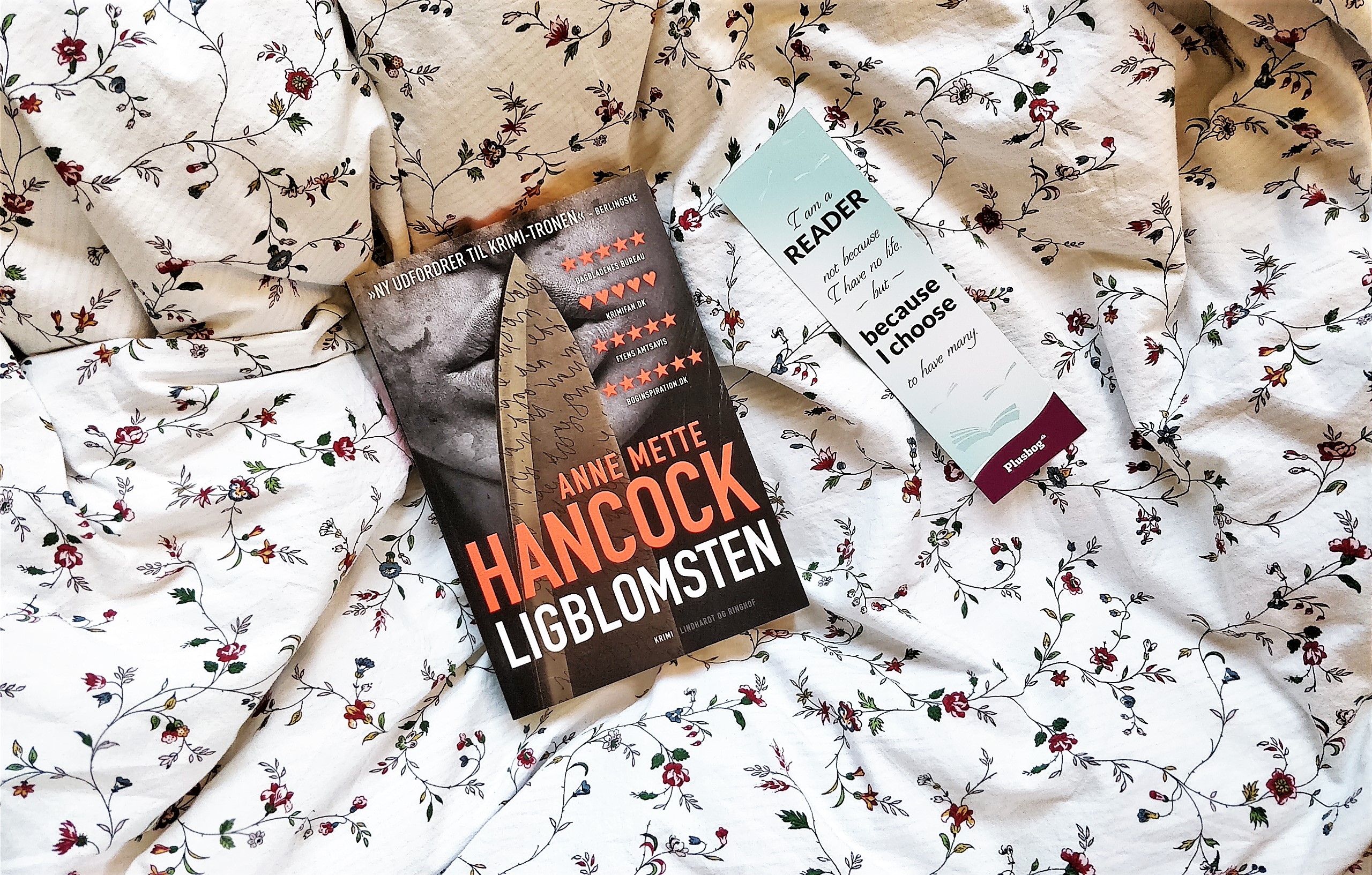The crime fiction book Ligblomsten by Anne Mette Hancock on a flowery background next to a bookmark