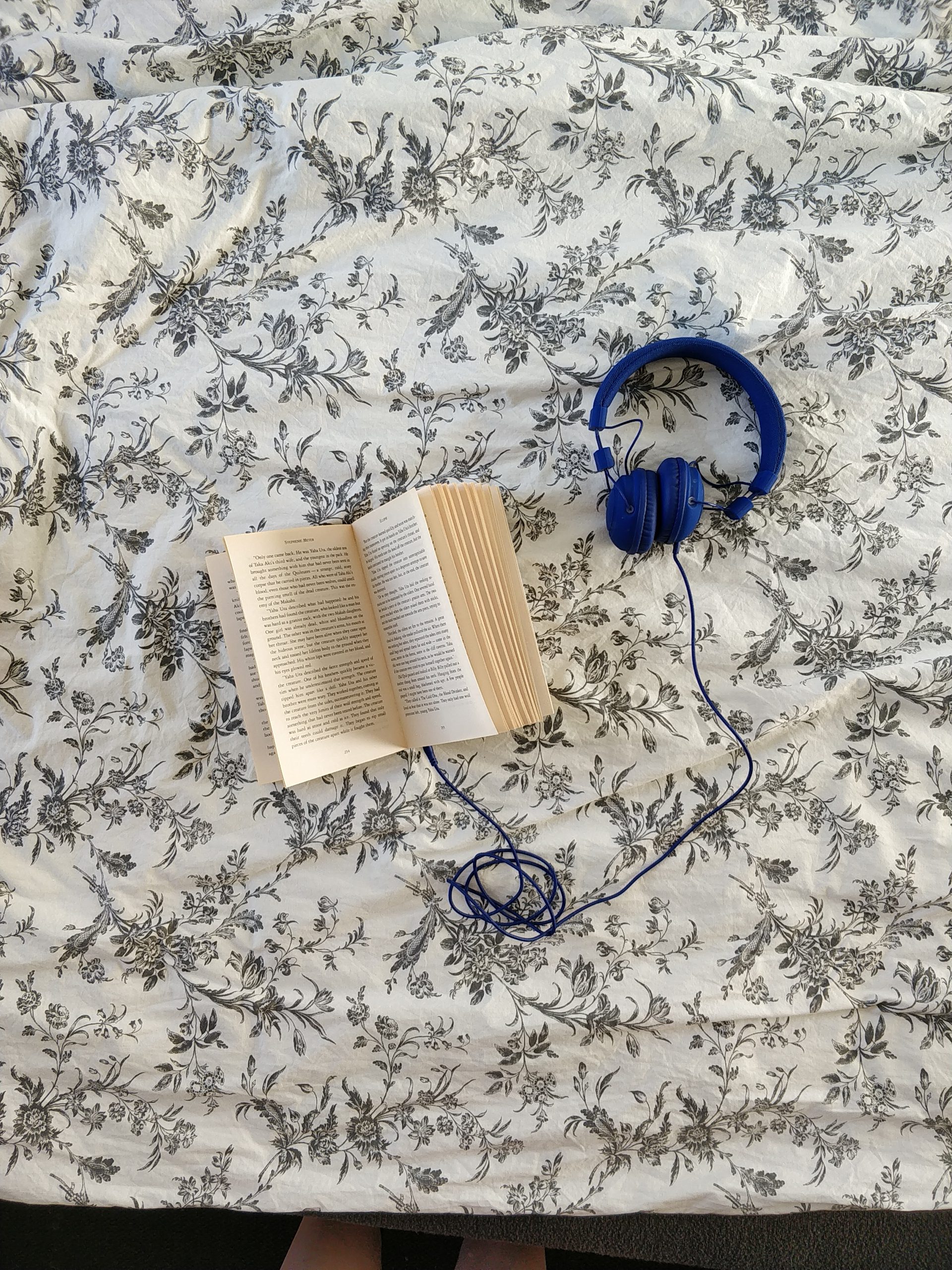 A book on a flowery background with a set of headphones attached to it